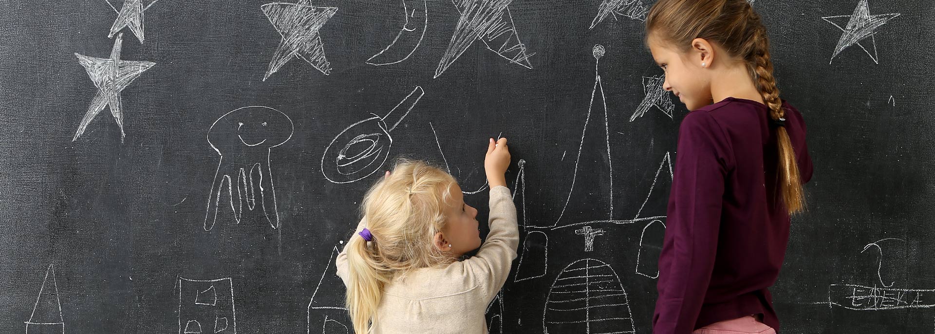 Kinder malen an Tafel mit Kreide